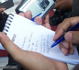 A person taking notes with a pen and a pad of paper