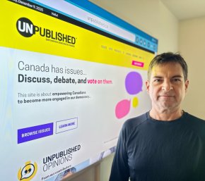 James O'Grady standing in front of big computer screen of his company's website: Unpublished.ca