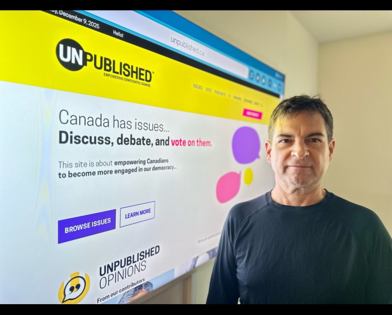 James O'Grady standing in front of big computer screen of his company's website: Unpublished.ca