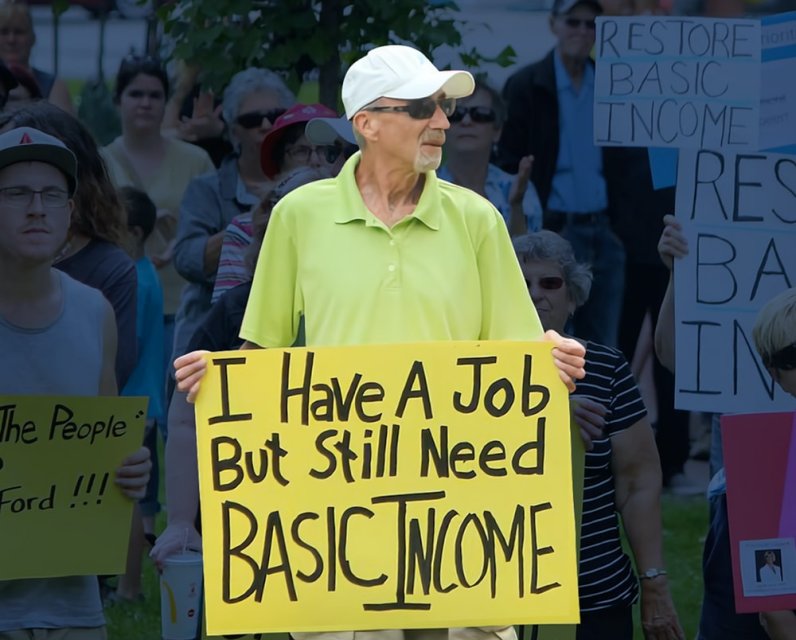 Man holding sign that says: I have a job but still need Basic Income